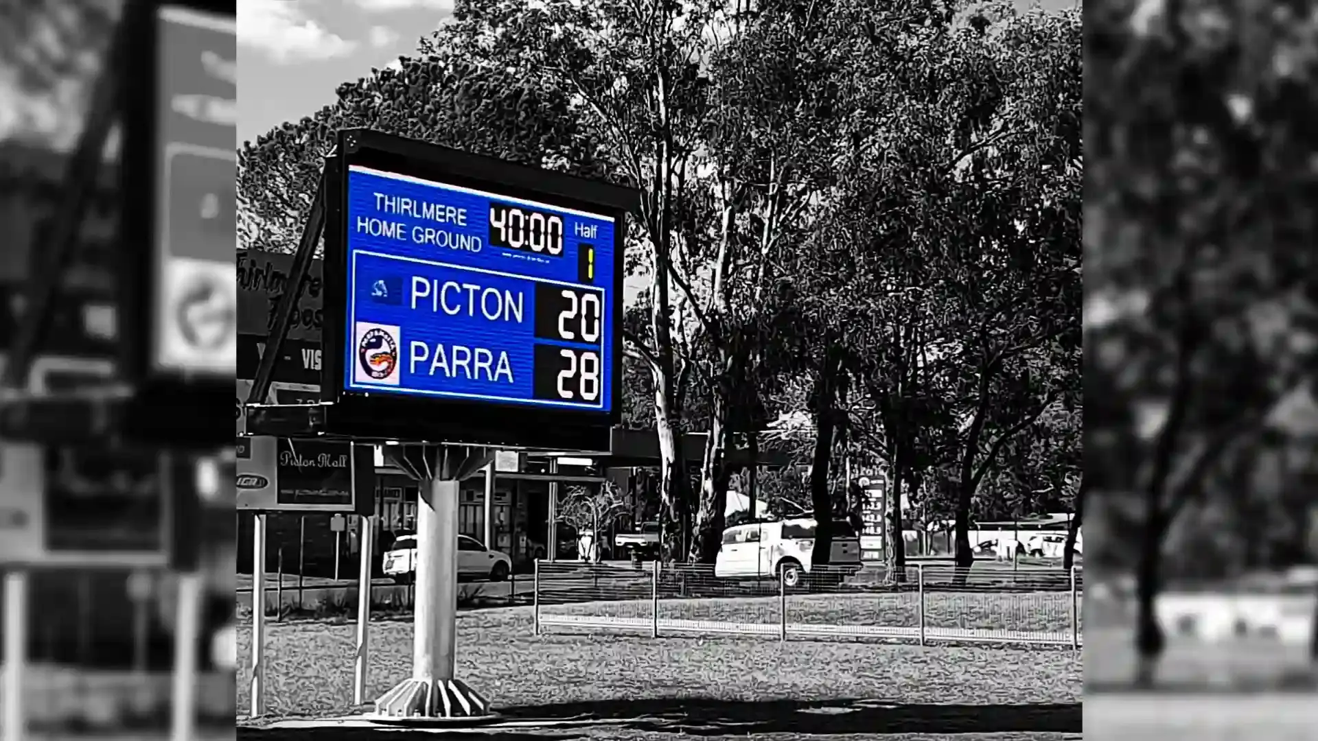 Sports stadium LED screen showing live scoreboard and replay footage